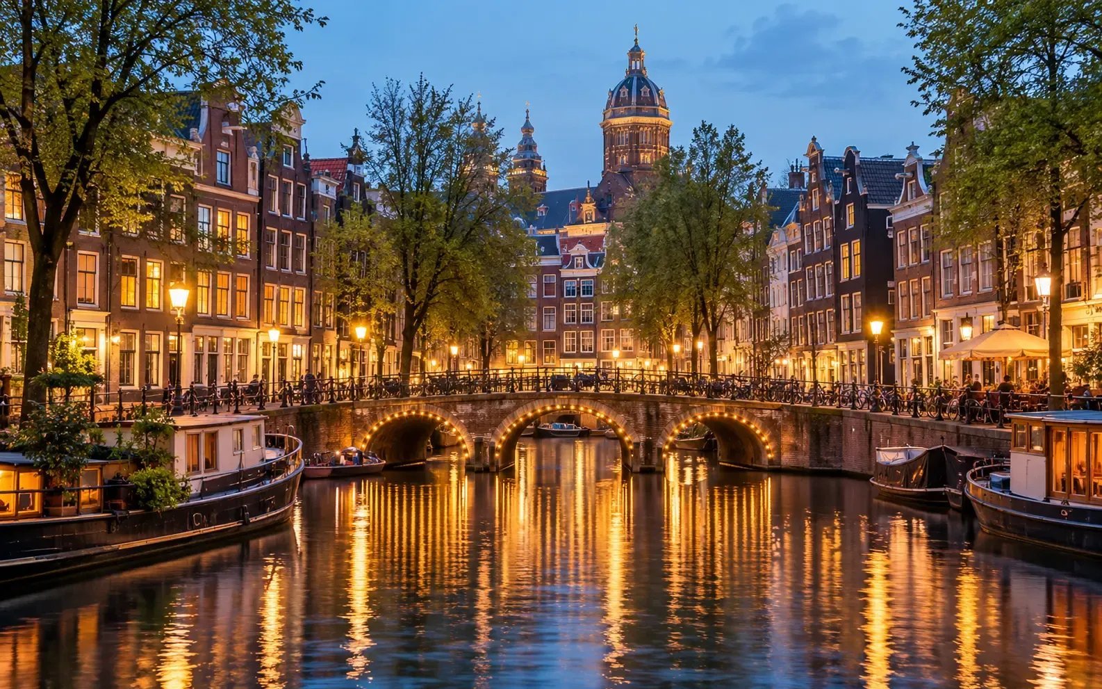 Canal histórico de Ámsterdam con casas estrechas de ladrillo y un puente iluminado en la hora azul